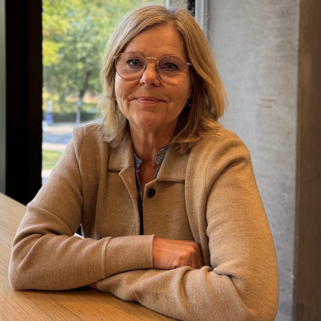 Porträtt på kvinna i blond page och glasögon och beige tröja